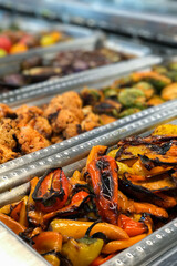 Delicious orange and yellow fire-roasted sweet peppers at a food and salad bar