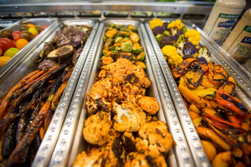 Assortment of roasted eggplant, carrots, tie-dye and sambal cauliflower, and sweet peppers at a salad bar