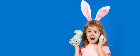 Excited child boy hunting easter eggs. Portrait of amazed, kid in rabbit costume with bunny ears having easter, isolated on blue background. Horizontal photo banner for website header design.