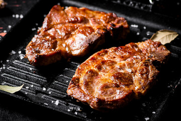 Grilled pork steak in a frying pan. 