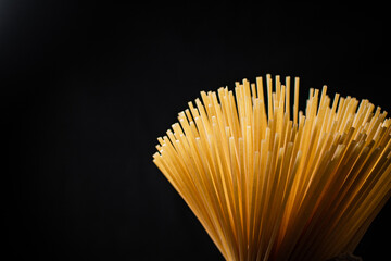 Not boiled spaghetti dry on a black background.