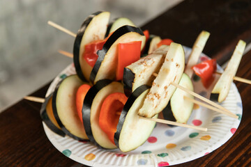 barbecue outside, the process of cooking vegetables, chopped eggplant and bell peppers strung on wooden skewers. outdoor recreation.