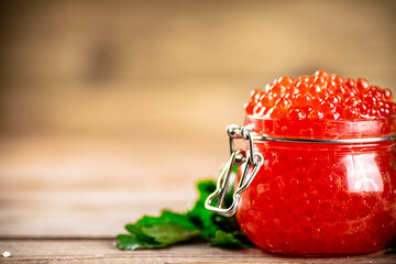 Red caviar in a glass jar with parsley. 