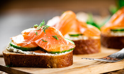 Salmon sandwich on a wooden cutting board. 