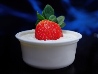 Delicious red organic strawberries in a cup with natural yogurt.