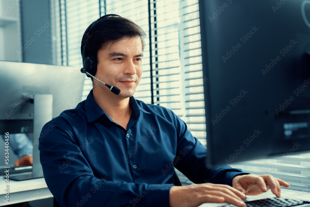 Aufkleber young competent asian male call center agent working at his computer while simultaneously speaking w