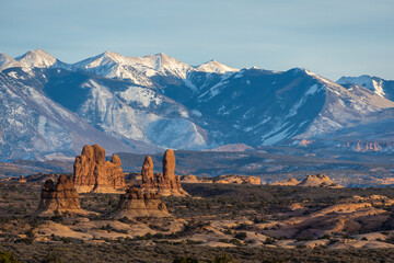 Rock formations with distant snow-covered mountains in the distance in Arches National Park.
