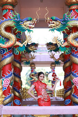 Fototapeta premium Portrait attractive Asian woman wearing traditional red cheongsam qipao dress in Naja Chinese shrine at Chonburi of Thailand, Chinese new year concept