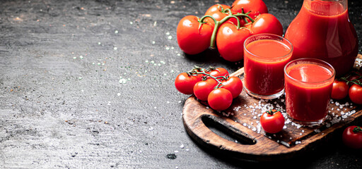 Obraz na płótnie Canvas Glasses of tomato juice on a cutting board. 