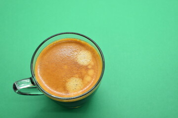 glass of hot black coffee put on green background