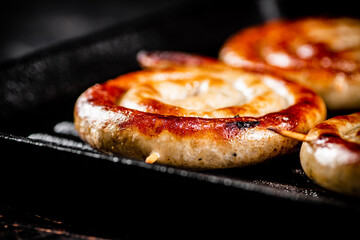 Grilled sausages in a frying pan. 