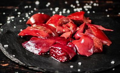 Pieces of raw liver on a stone tray with salt. 