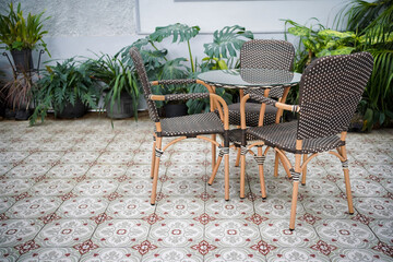 Several wooden chairs circle a table near a beautiful garden