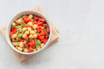 Healthy food chickpeas salad add tomato coriander in white bowl on wood background.