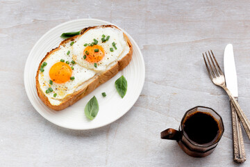Breakfast food fried egg on bread slice in plate and coffee on white wood table