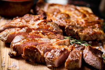 Slices of grilled steak pork on a wooden cutting board. 