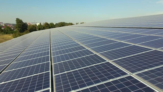Aerial view of solar power plant with blue photovoltaic panels mounted on industrial building roof for producing green ecological electricity. Production of sustainable energy concept