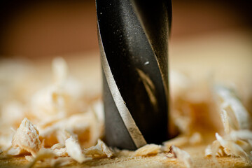 Piece of wood is drilled with shavings. 