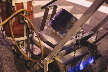 Process of making new road surface markings with line striping machine, workers improve city infrastructure, demarcation marking of pedestrian crossing with hot melted paint on asphalt pavement