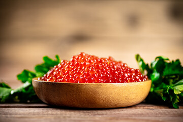 Red caviar in a plate on the table with parsley. 