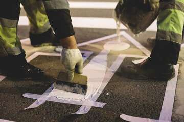 Process of making new road surface markings with line striping machine, workers improve city infrastructure, demarcation marking of pedestrian crossing with hot melted paint on asphalt pavement