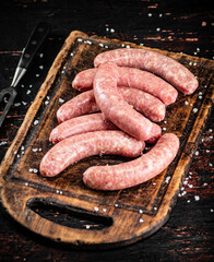 Raw sausages on a cutting board. 