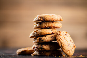 Pile of homemade cookies with pieces of milk chocolate on the table.