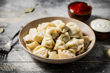 Dumplings in a plate with tomato sauce and sour cream. 