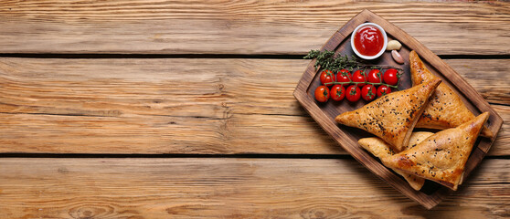 Board with tasty Uzbek samsas and tomatoes on wooden background with space for text