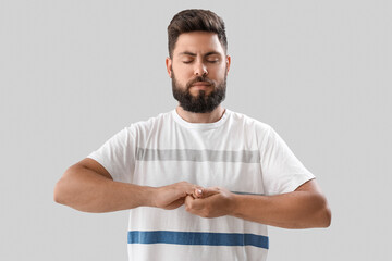 Handsome young man meditating on light background