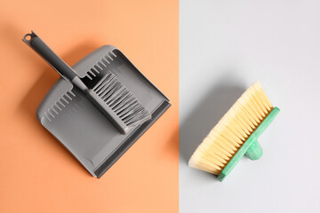 Dustpan and cleaning brushes on color background