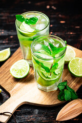 Mojito with pieces of lime on a cutting board.