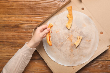 Female hand with pizza leftovers on wooden background