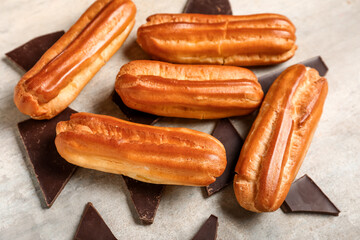 Composition with sweet eclairs and chocolate pieces on grunge background, closeup