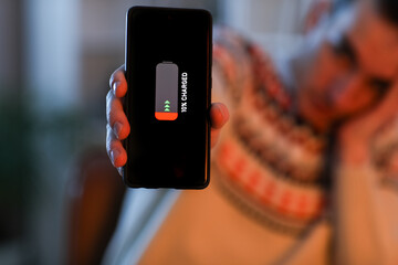 Young man with discharged mobile phone in office during blackout, closeup