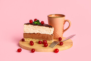 Tray with piece of birds milk cake, cranberries, mint leaves, fork and cup of drink on pink background