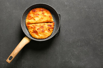 Frying pan with tasty chebureks on dark grunge background