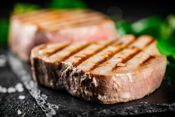 Grilled tuna on a stone board with parsley and salt. 