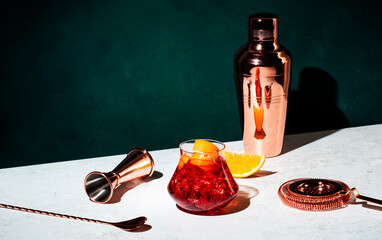 Boulevardier alcoholic cocktail with bourbon, vermouth, bitters, orange and ice. Dark green...