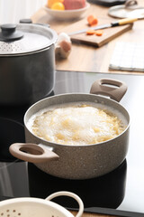 Cooking pot with boiling pasta on stove in kitchen