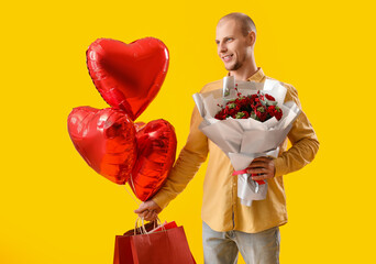 Young man with bouquet of flowers, bags and balloons on yellow background. Valentine's Day...