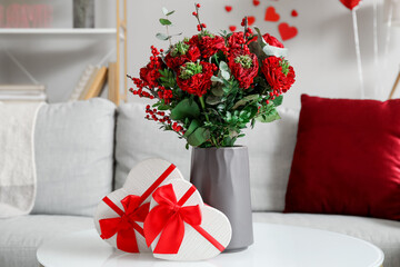 Vase with flowers and gifts for Valentine's Day on table in living room, closeup