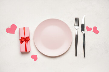 Table setting for Valentine's Day with gift and hearts on white background
