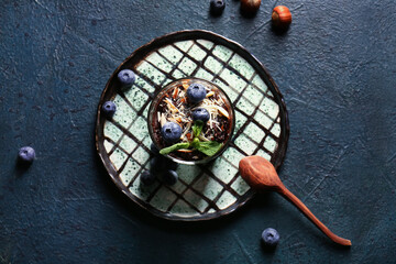 Fototapeta na wymiar Plate with bowl of delicious chocolate pudding, blueberry and almond on black table