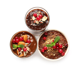 Glasses and bowl of delicious chocolate pudding with cranberry, almond and mint isolated on white background