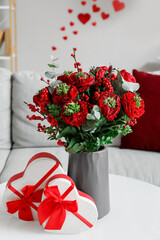 Vase with flowers and gifts for Valentine's Day on table in living room, closeup