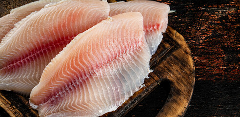 Raw fish fillet on a wooden cutting board. 