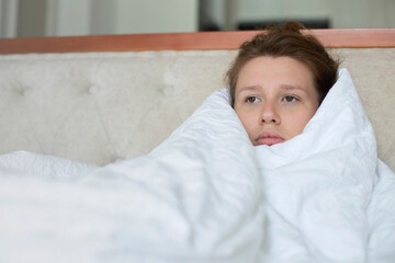 Portrait of young unhappy depressed girl, beautiful lazy lonely woman covering herself in blanket,...