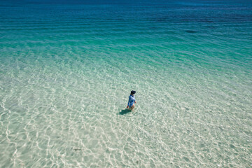 Aerial view of a woman walking in the clear blue water of Geographe Bay in Western Australia