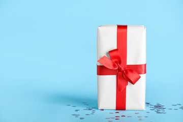 Gift box with beautiful bow and hearts on blue background. Valentine's Day celebration